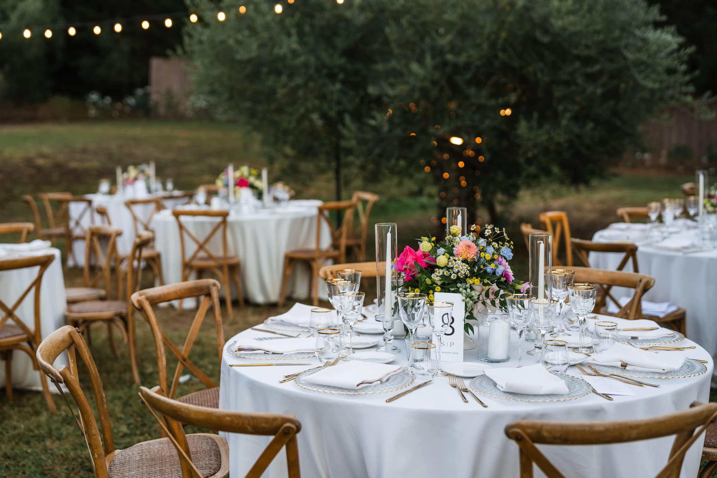 Festlich dekorierte Hochzeitstafel einer Gartenhochzeit mit Lichterketten, Kerzen und Blumenschmuck – geplant mit celebrateUs